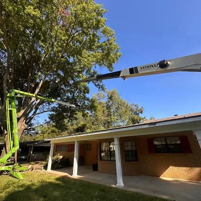 Crane boom extended over a house roof during tree work